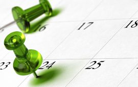 A green pushpin stuck in a calendar